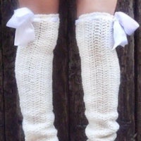 a woman's legs with white knitted leg warmers and bows