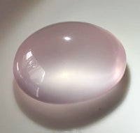 a pink quartz stone sitting on top of a white surface