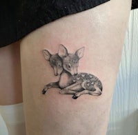 a tattoo of two deer on the thigh